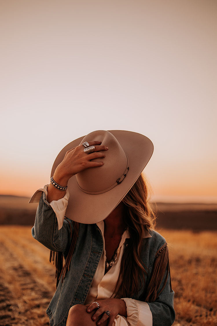 Crafted from 6X fur felt in buckskin, this hat features a 4” wide shovel brim paired with a tall brick crown that measures 4 1/2” tall. The hat is finished with a goat leather sweatband, a polished two tone metal 3-piece buckle set, a matching self-band, and a special edition royal blue satin liner.